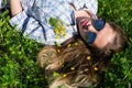 Young woman with sunglasses and little yellow flowers in blonde hair is lying down on green grass on bright sun. Royalty Free Stock Photo