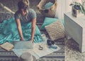 Young woman planning next travel vacation destination at home studying with laptop and paper map guide sitting on the carpet. Royalty Free Stock Photo