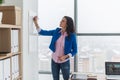 Young woman planning writing day plan on white board, holding marker in right hand