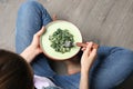 Young woman with plate of tasty spinach on wooden floor, closeup