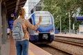 Young woman on the platform waiting for the train. Beautiful girl at the train station. Travel by train. Railway station in