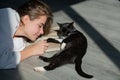 Young woman play with fluffy cat. Cat lies near woman face. The fluffy black cat comfortably settled to sleep or to play Royalty Free Stock Photo