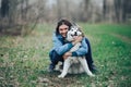 Young woman play with husky dog for a walk in spring forest. laughing having fun, happy with pet