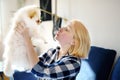 Young woman play with 2-month old pomeranian spitz puppy. Cute fluffy small dog