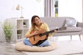 Young woman playing acoustic guitar in room Royalty Free Stock Photo