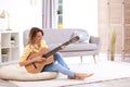 Young woman playing acoustic guitar in room Royalty Free Stock Photo