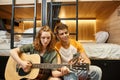 young woman playing acoustic guitar to