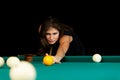 Young woman playing billiard. Black background. Royalty Free Stock Photo