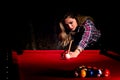 Young woman playing billiards in the dark billiard club Royalty Free Stock Photo