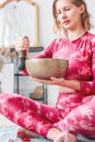 Young woman playing on brass Tibetan singing bowl. Sound therapy and meditation Royalty Free Stock Photo