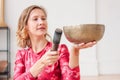 Young woman playing on brass Tibetan singing bowl. Sound therapy and meditation Royalty Free Stock Photo