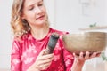 Young woman playing on brass Tibetan singing bowl. Sound therapy and meditation Royalty Free Stock Photo