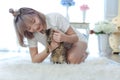 Young woman playing with a cat in a living room covered with white carpet Royalty Free Stock Photo