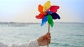 Young woman playing with a colorful spinning pinwheel on the sandy sea beach. Summer holiday, travel, and positive emotions Royalty Free Stock Photo