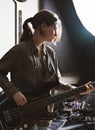 young woman playing electric bass guitar in a studio. rock musician rehearsal room. sound recording and check Royalty Free Stock Photo