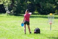 Young woman playing flying disc golf sport game in the public park or nature