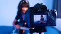 Young woman playing guitar in front of the camera. recording demo or giving online class