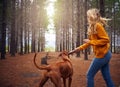 Young woman playing with her dog in the forest