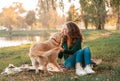 Young woman playing with her dog golden retriever at the autumn park Royalty Free Stock Photo