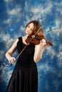 Young woman playing the violin against blue background