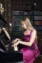 Young woman plays piano in room with bookshelves
