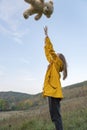 Young woman plays with teddy bear in clearing on background of hills or mountains. Girl with soft toy outdoors Royalty Free Stock Photo