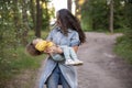 Young woman plays with toddler girl in yellow in park Royalty Free Stock Photo