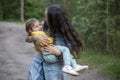 Young woman plays with toddler girl in yellow in park Royalty Free Stock Photo