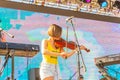 A young woman plays the violin on an open summer stage