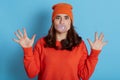 Young woman with pleasant appearance chewing gum and blowing hair bubble isolated over blue background, looks scared, being in Royalty Free Stock Photo