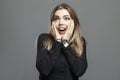 The young woman is pleasantly surprised. Beautiful blonde in a black shirt feels happy. Positiveness and joy. Gray background