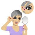 Young woman plucking her eyebrows with tweezers looking at mirror