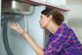 Young woman with plumber problem in kitchen Royalty Free Stock Photo