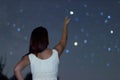 Young woman pointing on defocused Star. Woman under starry night, Woman pointing to Defocused Scorpius Constellation