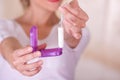 Young woman pointing in front of her, a menstruation cotton tampon in one hand and with her other hand a plastic purple