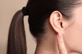 Young woman pointing at her ear on beige background, closeup Royalty Free Stock Photo