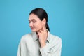 Young woman pointing at her ear on light blue background Royalty Free Stock Photo