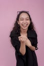 A young woman pointing and making fun of someone, mocking their appearance. Isolated on a light pink background