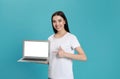 Young woman pointing at modern laptop with blank screen on light blue background Royalty Free Stock Photo