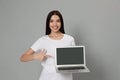 Young woman pointing at modern laptop with blank screen on light grey background Royalty Free Stock Photo