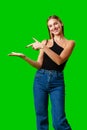 Young Woman Pointing at Something against green background