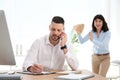 Woman popping paper bag behind her colleague in office. April fool`s day