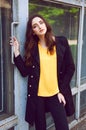 Young woman portrait in black trenchcoat and yellow blouse