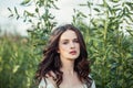 Young woman portrait. Perfect female face. Brunette girl with curly hair outdoors on green leaves background Royalty Free Stock Photo