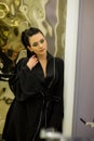 Young woman posing in black silk bathrobe. sexy housewife concept. Girl in a black bathrobe indoors. Beauty saloon Royalty Free Stock Photo