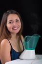Young woman posing for camera behind of a medical vaporizer nebulizer machine on black background