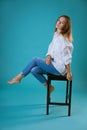 Young woman posing on chair in white shirt on blue background Royalty Free Stock Photo