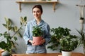 Young woman posing with greenery at home and holding potted plant Royalty Free Stock Photo