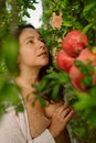 Young woman posing with ripe red pomegranates tree. concept of healthy autumn and winter lifestyle and diet, outdoors with nature