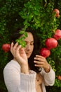 Young woman posing with ripe red pomegranates tree. concept of healthy autumn and winter lifestyle and diet, outdoors with nature